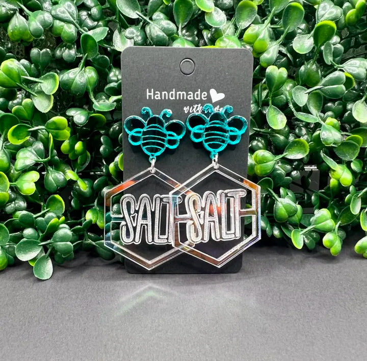 Teal and silver earrings on a 'SALT' branded card with green foliage in the background